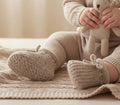 Coffee-coloured baby booties worn on baby's feet